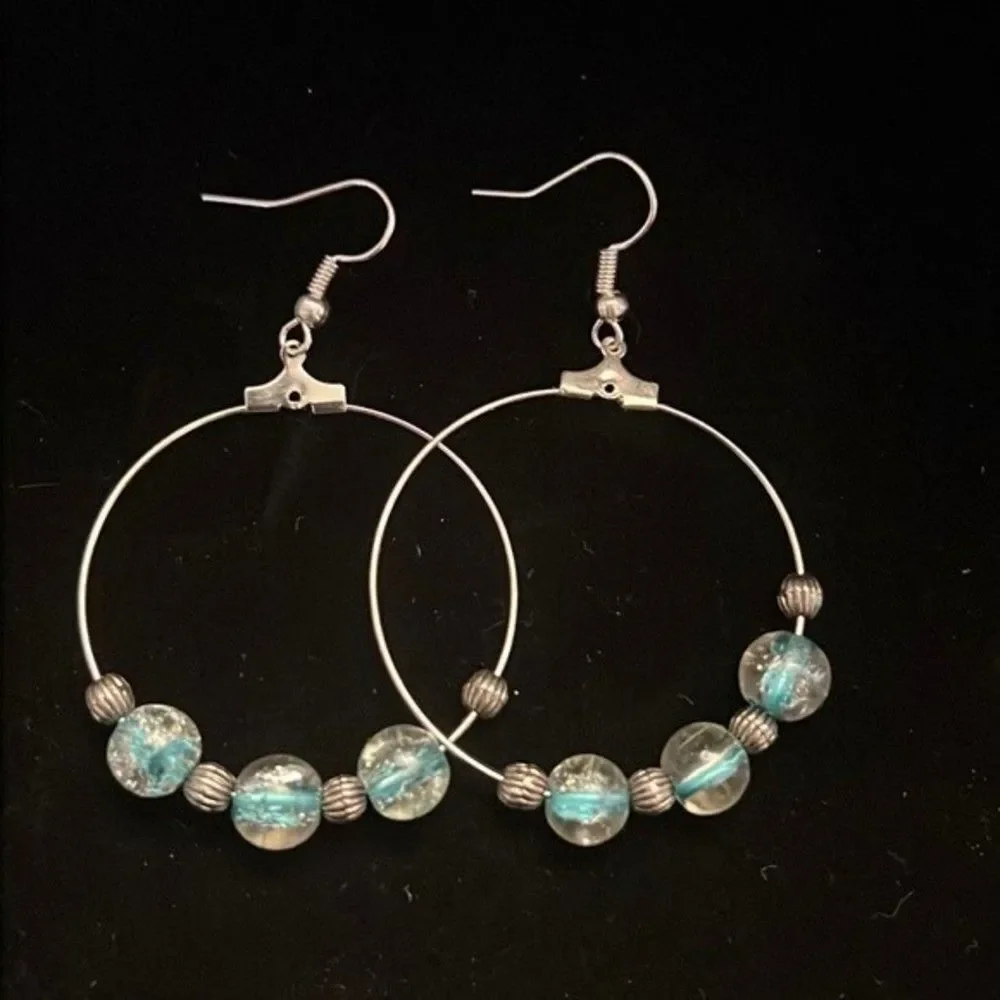 Handcrafted silver tone hoop earrings with clear and blue beading.